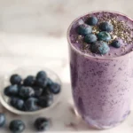 Blueberry cottage cheese smoothie in a tall glass with fresh toppings
