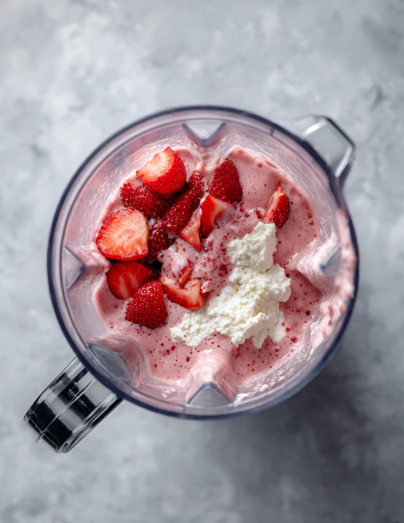 Strawberry cheesecake smoothie ingredients blending in high-speed blender