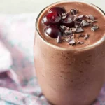 Chocolate cherry protein smoothie with halved cherry topping