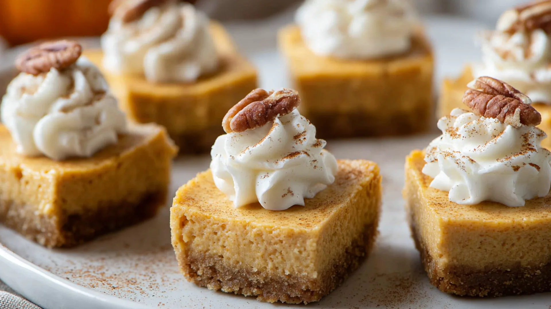 A tray of Healthy Pumpkin Cheesecake Bites with whipped cream and pecans.