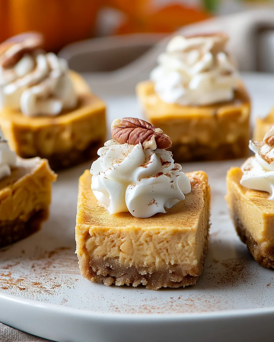 Pumpkin cheesecake bites served on a plate with whipped cream.